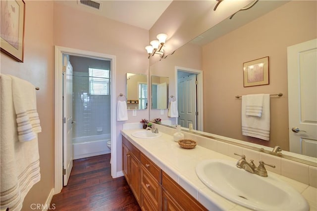 bathroom featuring a sink, toilet, wood finished floors, and visible vents
