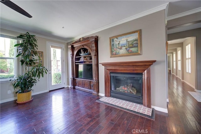 unfurnished living room with crown molding, a glass covered fireplace, wood finished floors, baseboards, and ceiling fan
