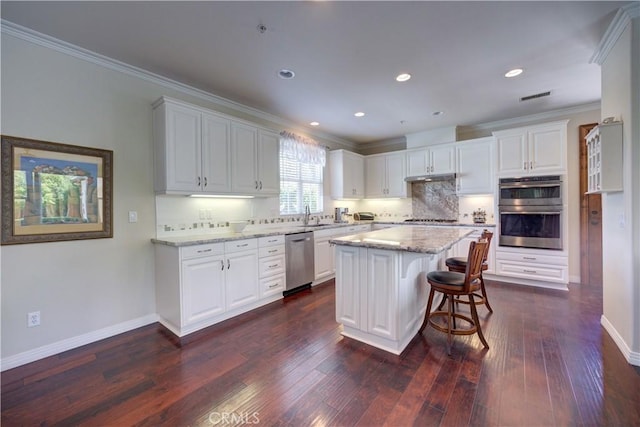 kitchen with white cabinets, appliances with stainless steel finishes, ornamental molding, and a sink