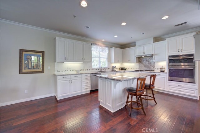 kitchen with visible vents, crown molding, white cabinets, a sink, and stainless steel appliances