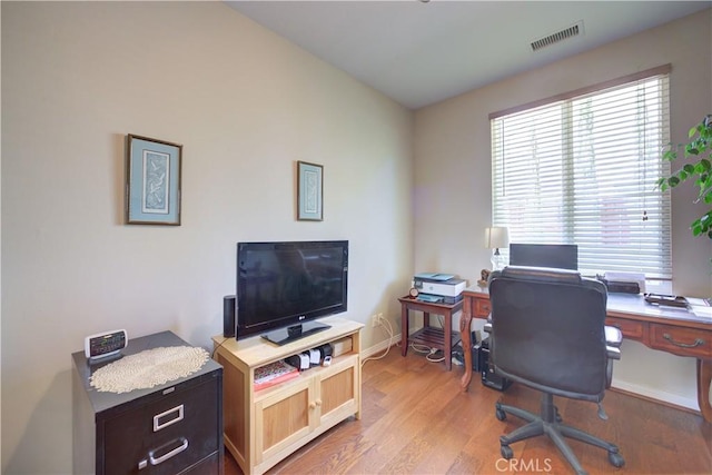 office space featuring baseboards, light wood finished floors, and visible vents