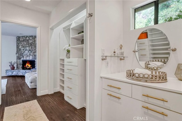spacious closet with a stone fireplace and dark wood-style floors