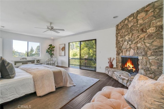 bedroom with access to outside, baseboards, wood finished floors, and multiple windows