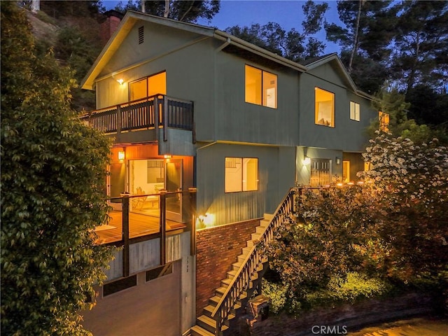 back of house with a chimney, stucco siding, stairway, and a balcony