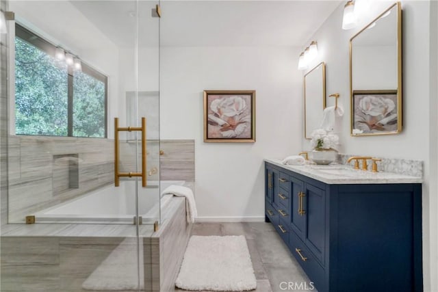 bathroom featuring double vanity, a shower with door, baseboards, a tub, and a sink