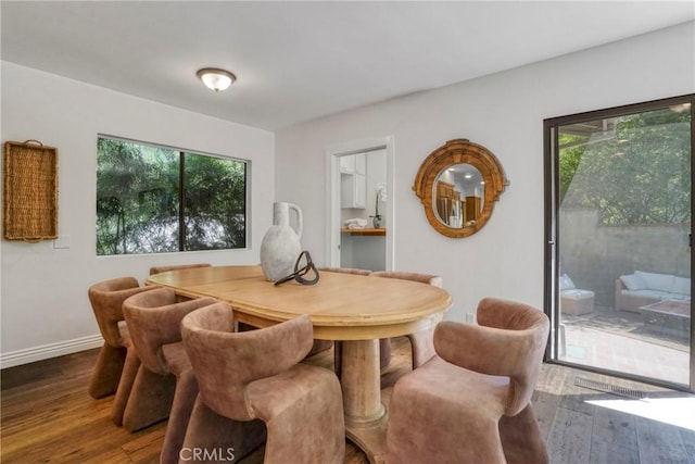 dining area featuring baseboards, wood finished floors, and a healthy amount of sunlight