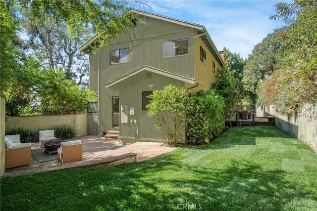 rear view of house with a lawn, a fenced backyard, an outdoor living space with a fire pit, and a patio area