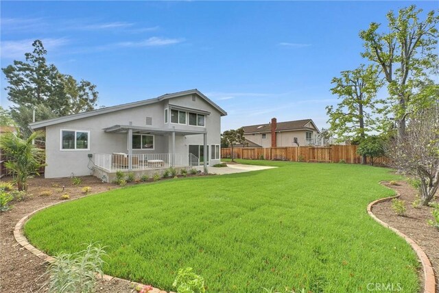 back of house featuring a yard, a patio, a fenced backyard, and stucco siding