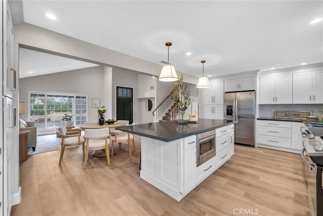 kitchen with light wood-style flooring, lofted ceiling, dark countertops, and stainless steel appliances