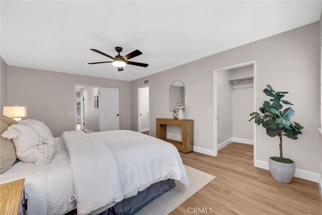 bedroom featuring ceiling fan, visible vents, light wood-type flooring, baseboards, and a spacious closet