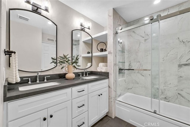 bathroom with visible vents, a sink, double vanity, and bath / shower combo with glass door