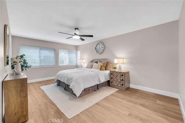 bedroom with a ceiling fan, baseboards, and light wood-style flooring