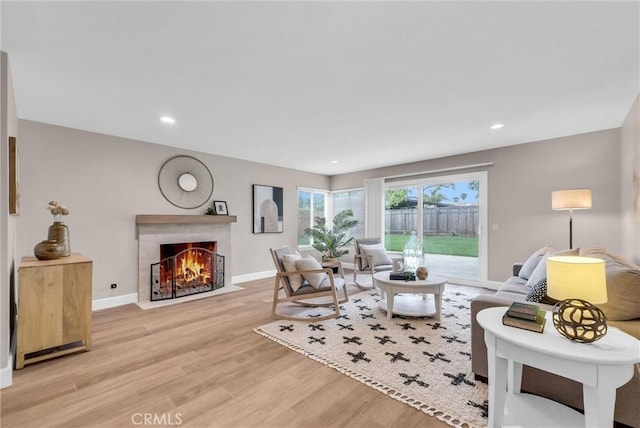 living area featuring light wood-style floors, baseboards, a fireplace, and recessed lighting