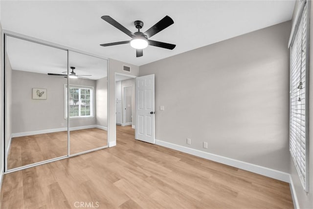 unfurnished bedroom with baseboards, a closet, light wood finished floors, and visible vents