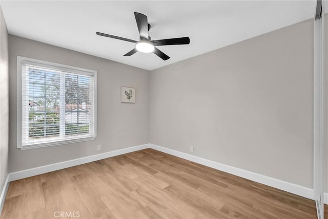 spare room with baseboards, light wood-style flooring, and ceiling fan