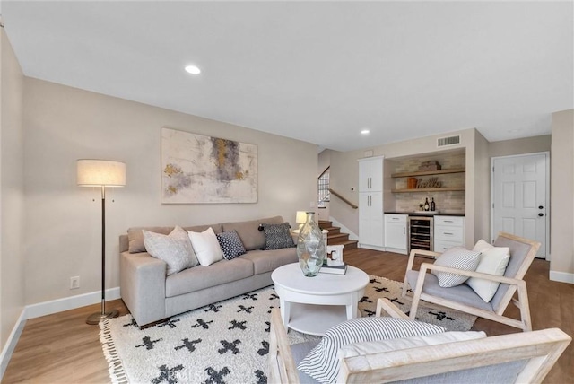 living area with visible vents, wine cooler, baseboards, light wood-style floors, and indoor bar