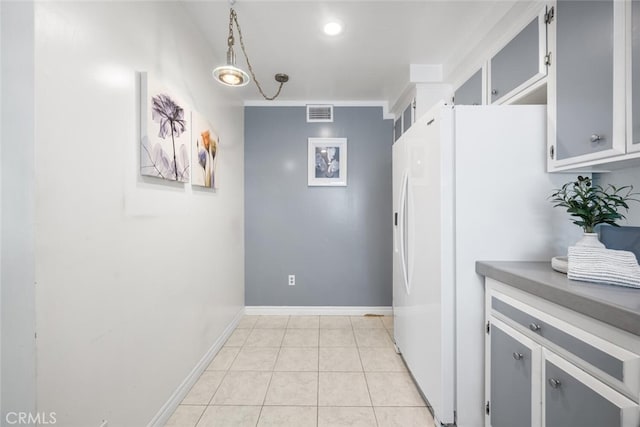 kitchen featuring baseboards, freestanding refrigerator, light tile patterned floors, and visible vents