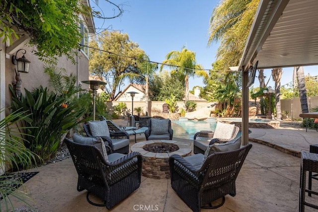 view of patio featuring a pool with connected hot tub, a fenced backyard, and an outdoor fire pit