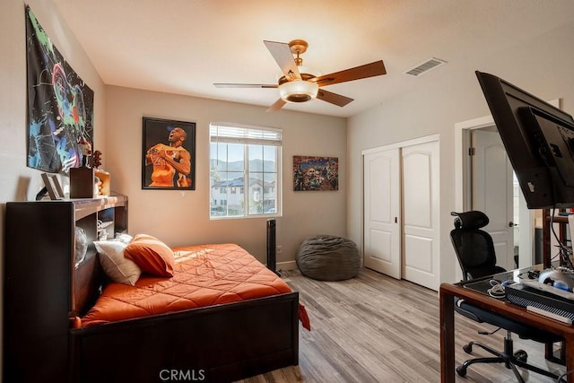 bedroom with ceiling fan, baseboards, wood finished floors, visible vents, and a closet