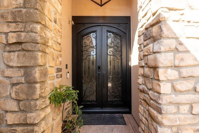 entrance to property featuring french doors and stone siding