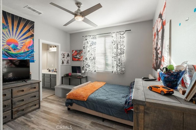 bedroom featuring a ceiling fan, visible vents, a sink, light wood-style floors, and ensuite bathroom