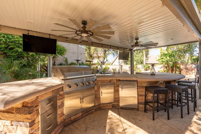 view of patio featuring exterior kitchen, a ceiling fan, and outdoor wet bar