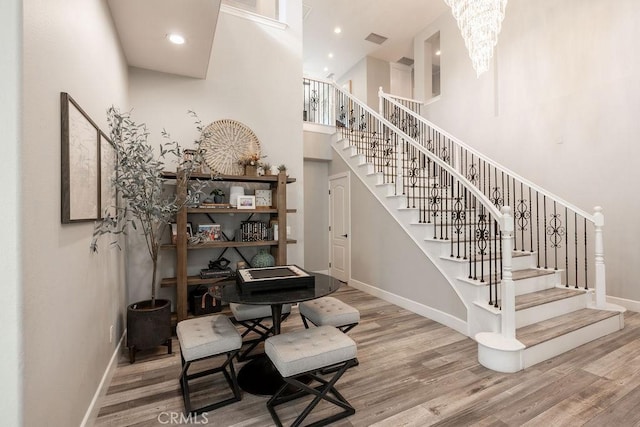 stairway with baseboards, recessed lighting, a high ceiling, and wood finished floors