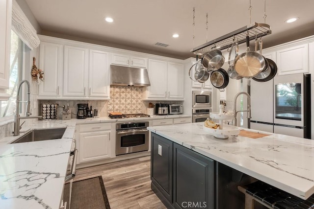 kitchen with a sink, white cabinetry, appliances with stainless steel finishes, and under cabinet range hood