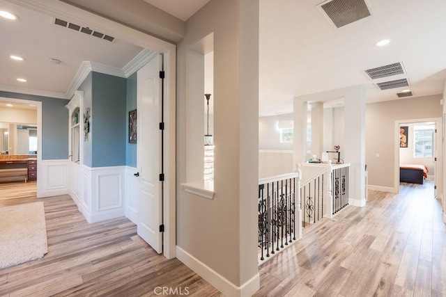 hallway with visible vents, light wood finished floors, and a wealth of natural light