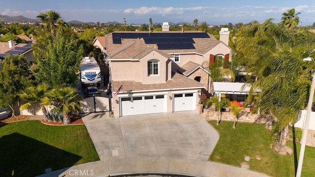 view of front facade with driveway, solar panels, a front yard, an attached garage, and stucco siding