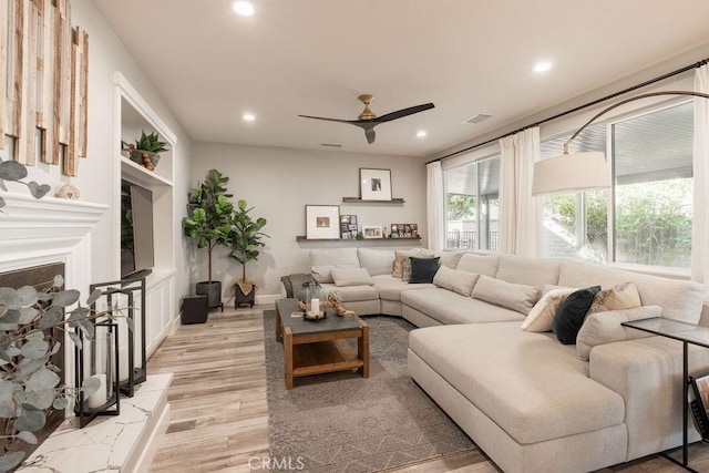 living room featuring ceiling fan, visible vents, a fireplace, light wood-style floors, and recessed lighting