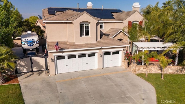 traditional-style home with stucco siding, a chimney, a gate, concrete driveway, and solar panels