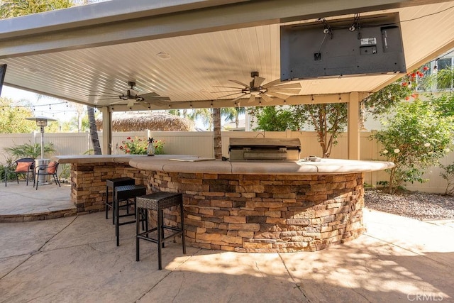 view of patio / terrace featuring a fenced backyard, ceiling fan, outdoor wet bar, and area for grilling