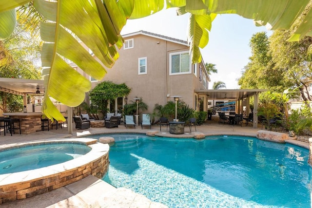 view of swimming pool with ceiling fan, a pool with connected hot tub, outdoor dry bar, a patio, and outdoor lounge area