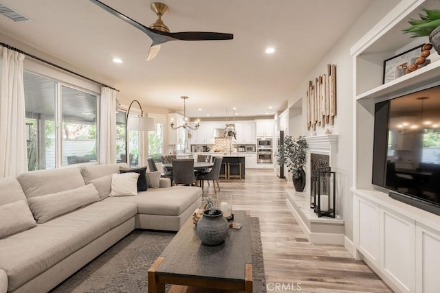 living room with visible vents, recessed lighting, ceiling fan with notable chandelier, and a healthy amount of sunlight