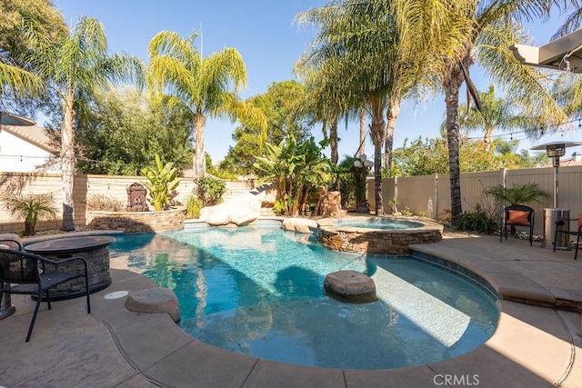 view of swimming pool with a pool with connected hot tub, a fenced backyard, and a patio area