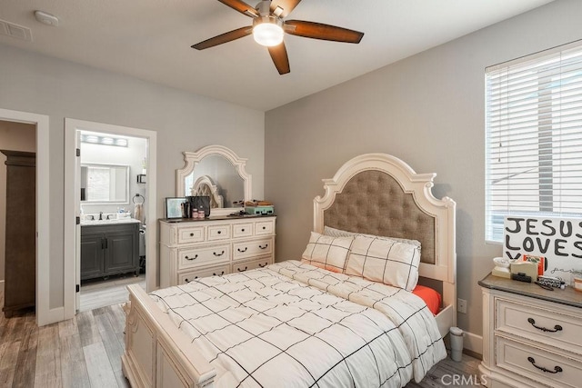 bedroom featuring visible vents, light wood-style flooring, ensuite bathroom, and multiple windows