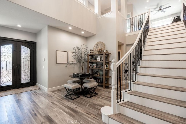entryway with french doors, baseboards, wood finished floors, and stairway