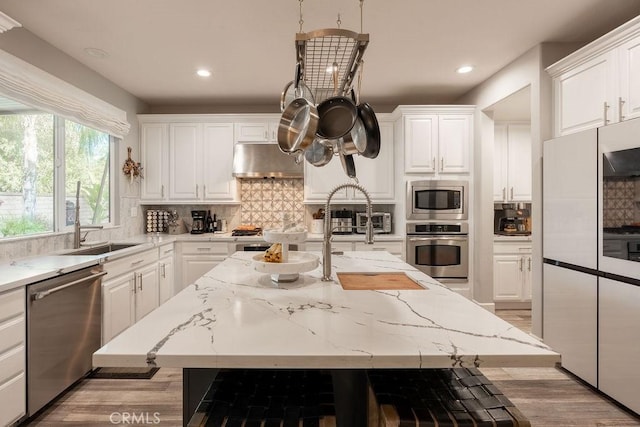 kitchen featuring backsplash, stainless steel appliances, white cabinetry, and under cabinet range hood