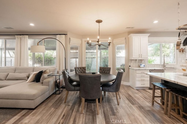 dining area featuring an inviting chandelier, light wood-type flooring, and visible vents