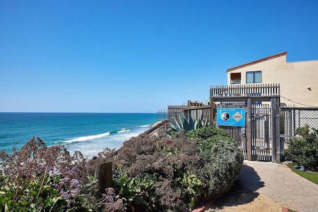 water view with fence, a gate, and a beach view