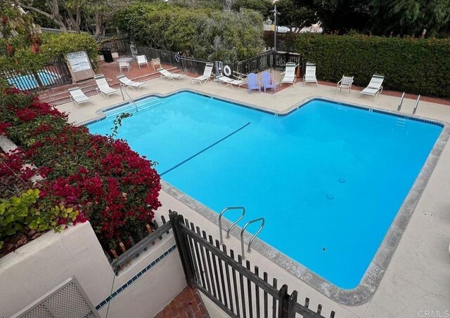 community pool with a patio and fence