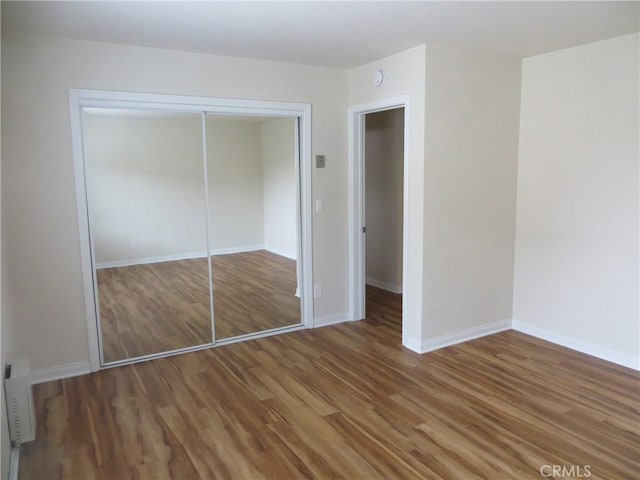 unfurnished bedroom with baseboards, a closet, and wood finished floors