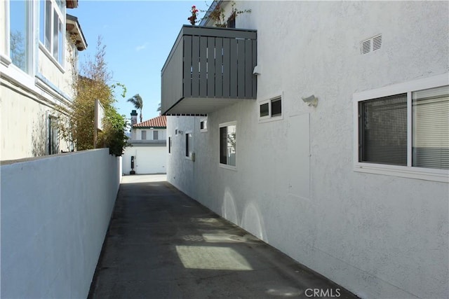 view of side of home with an outdoor structure, stucco siding, and fence