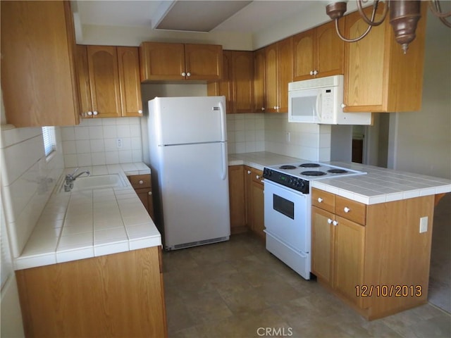 kitchen with brown cabinetry, backsplash, a sink, tile counters, and white appliances