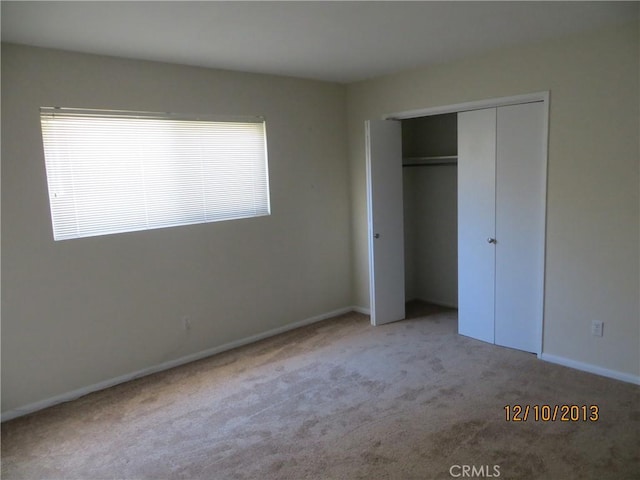 unfurnished bedroom with carpet flooring, baseboards, and a closet