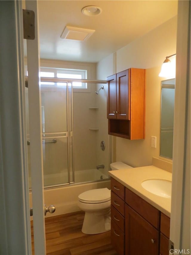 bathroom featuring vanity, combined bath / shower with glass door, toilet, and wood finished floors