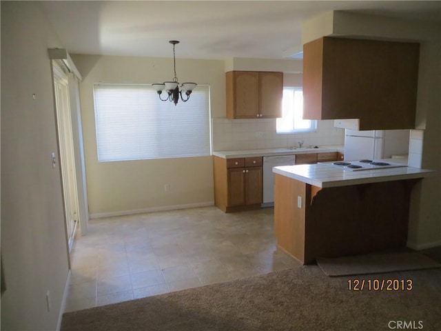 kitchen featuring decorative backsplash, light countertops, baseboards, a chandelier, and white appliances