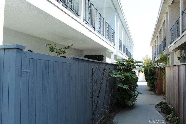 view of side of property with stucco siding and fence