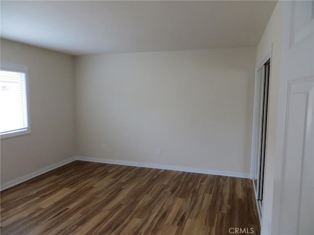 empty room with baseboards and dark wood-style flooring